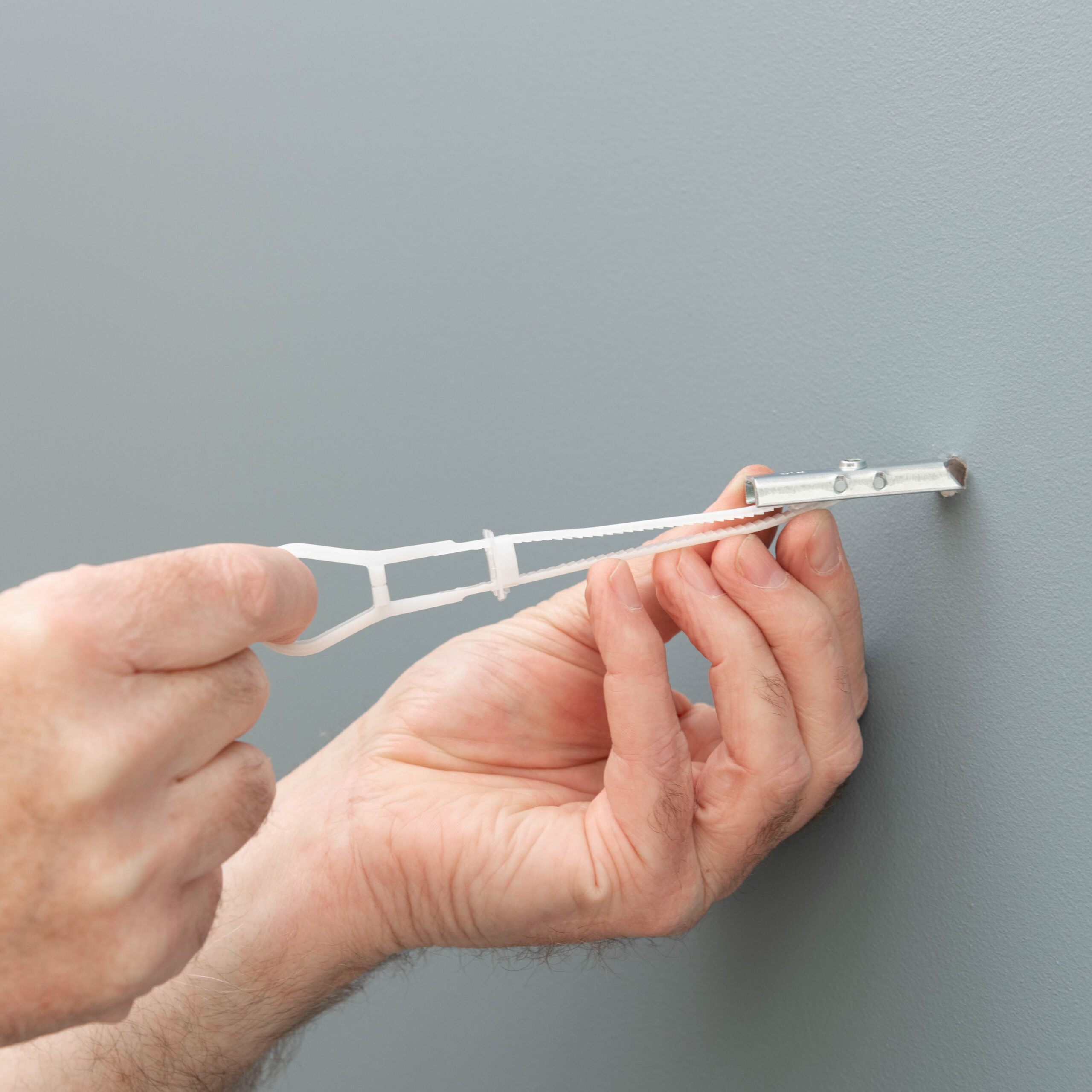 Corefix Strap Hollow Cavity Wall Fixing in sue: hands inserting the fixing into a hole in the wall